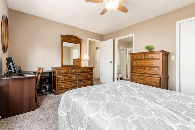 carpeted bedroom with ensuite bath and ceiling fan