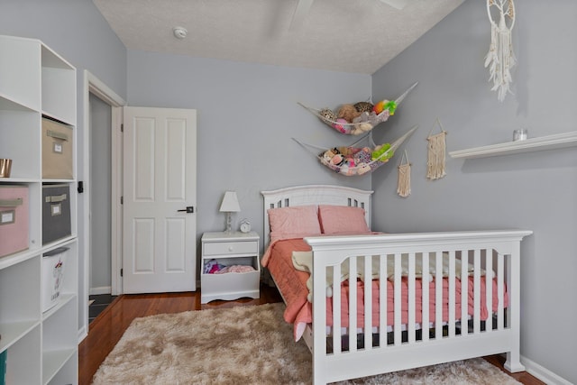 bedroom featuring a textured ceiling, baseboards, and wood finished floors