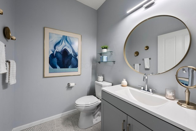 half bathroom featuring vanity, toilet, baseboards, and tile patterned flooring