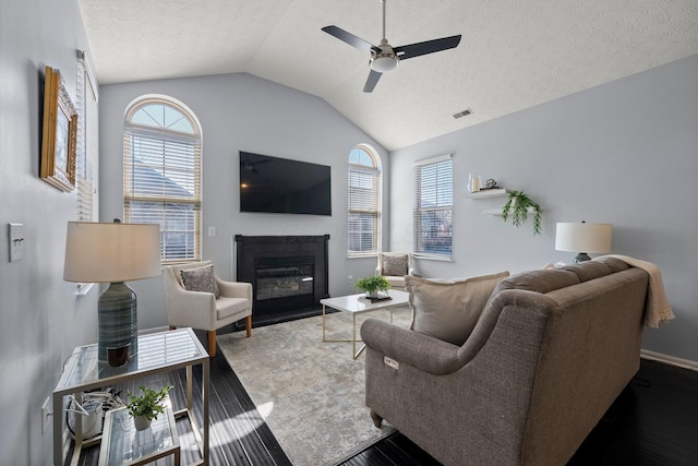 living area featuring a glass covered fireplace, a healthy amount of sunlight, visible vents, and ceiling fan