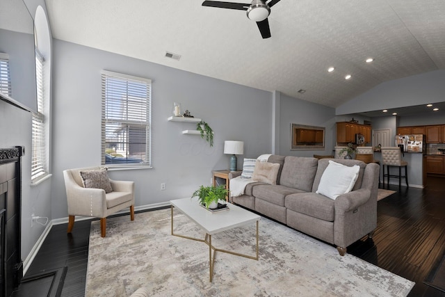 living area featuring visible vents, a ceiling fan, wood finished floors, baseboards, and lofted ceiling