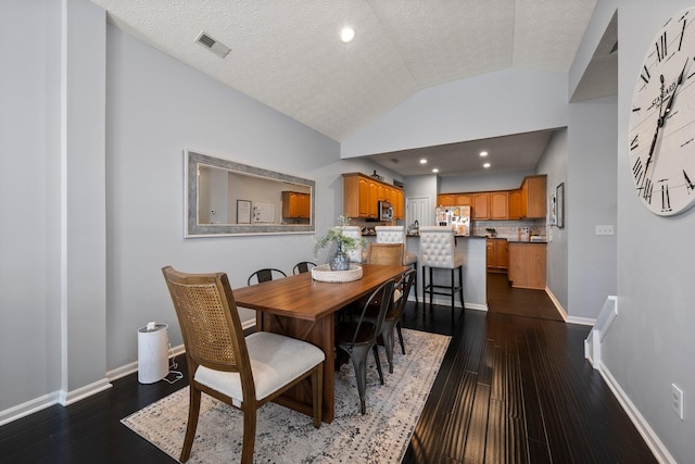 dining area with dark wood finished floors, lofted ceiling, baseboards, and visible vents