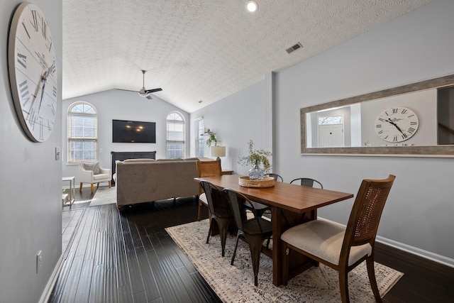 dining room with a ceiling fan, baseboards, visible vents, lofted ceiling, and dark wood-type flooring