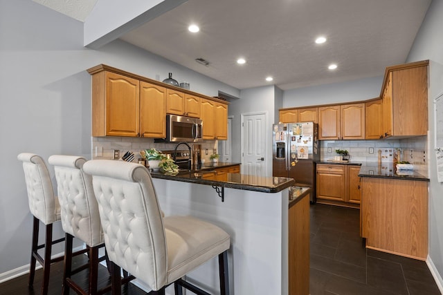 kitchen featuring a breakfast bar, a peninsula, recessed lighting, stainless steel appliances, and dark countertops