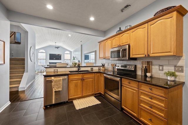 kitchen with visible vents, lofted ceiling, a peninsula, stainless steel appliances, and a sink