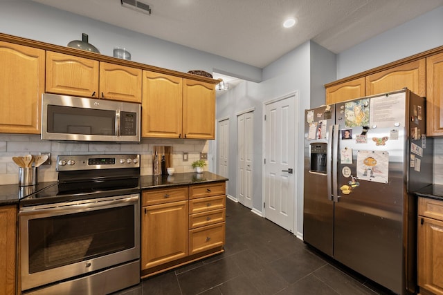 kitchen with visible vents, appliances with stainless steel finishes, dark tile patterned floors, and decorative backsplash