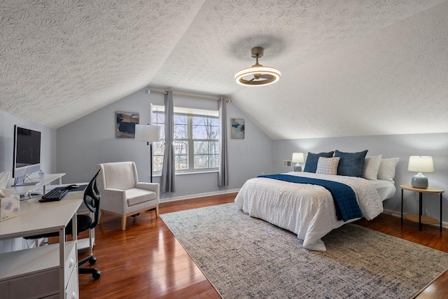 bedroom with baseboards, wood-type flooring, a textured ceiling, and vaulted ceiling