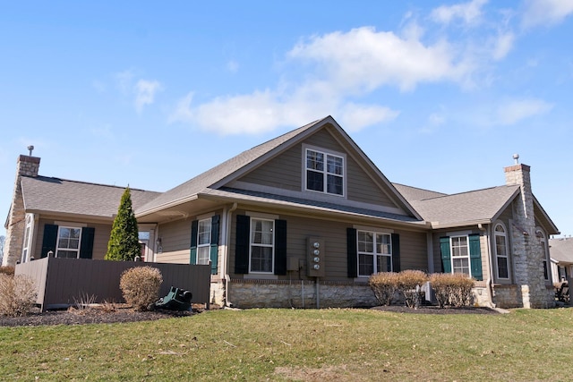 view of front of house featuring a front yard, roof with shingles, and a chimney