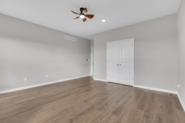 unfurnished bedroom featuring baseboards, visible vents, a ceiling fan, a closet, and wood finished floors