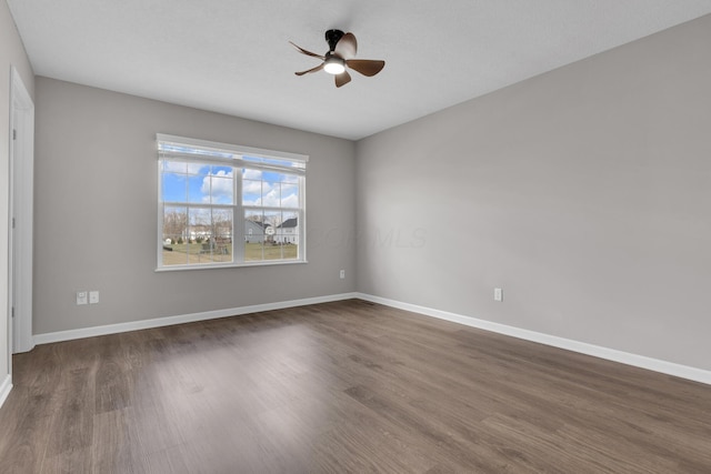 unfurnished room with dark wood-style floors, ceiling fan, and baseboards