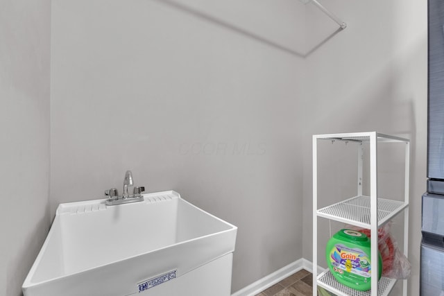 clothes washing area featuring baseboards and a sink