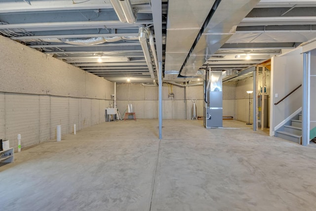 unfinished basement with heating unit, stairs, and water heater