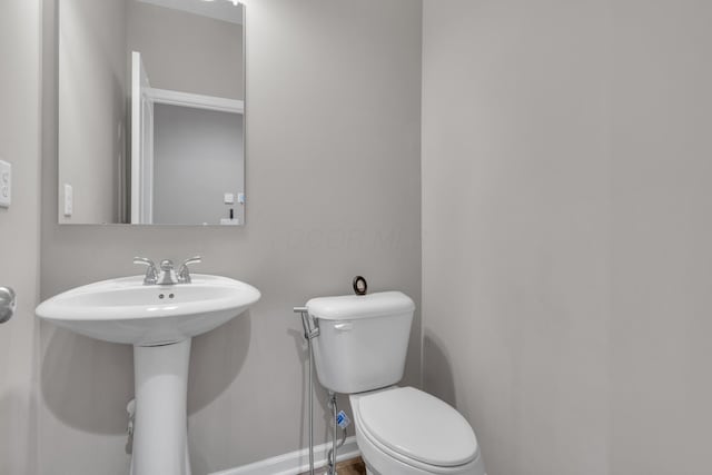 bathroom featuring baseboards, toilet, and a sink