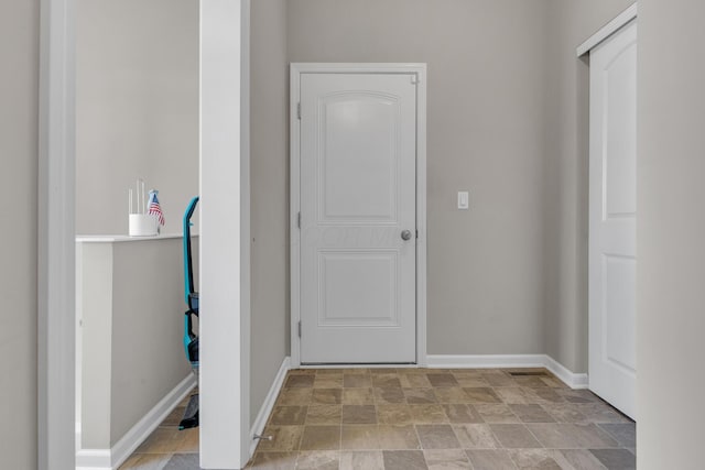 hallway with stone finish floor and baseboards