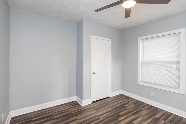 empty room with dark wood finished floors, baseboards, and ceiling fan