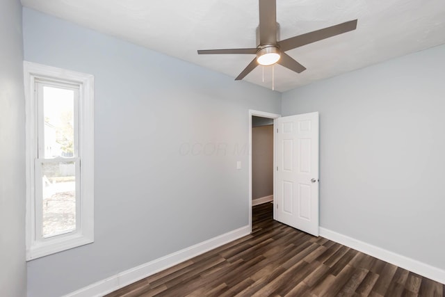 spare room with a ceiling fan, dark wood-style flooring, and baseboards