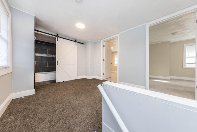 spare room featuring baseboards, a barn door, and carpet floors