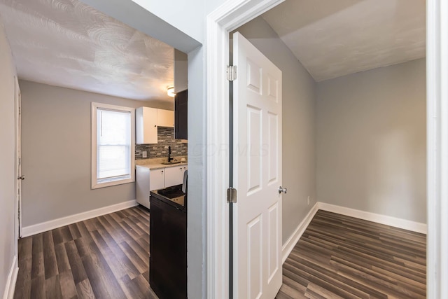 kitchen with baseboards, light countertops, a sink, and tasteful backsplash