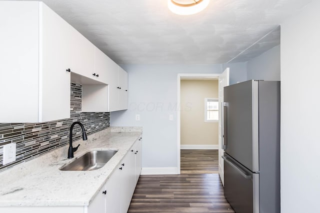 kitchen with dark wood finished floors, tasteful backsplash, white cabinetry, a sink, and freestanding refrigerator