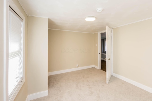 unfurnished bedroom featuring baseboards, ornamental molding, and light colored carpet