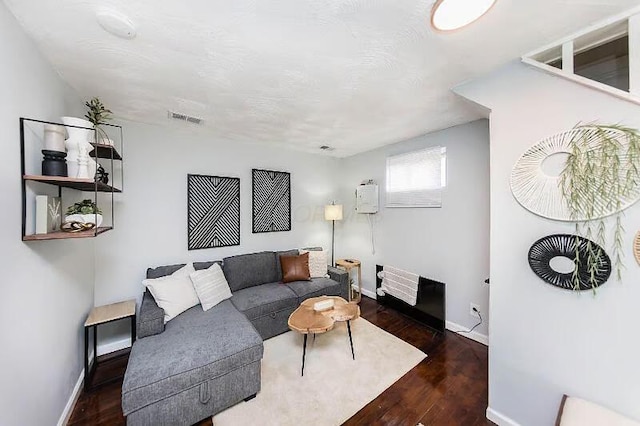 living room featuring baseboards, visible vents, and wood finished floors