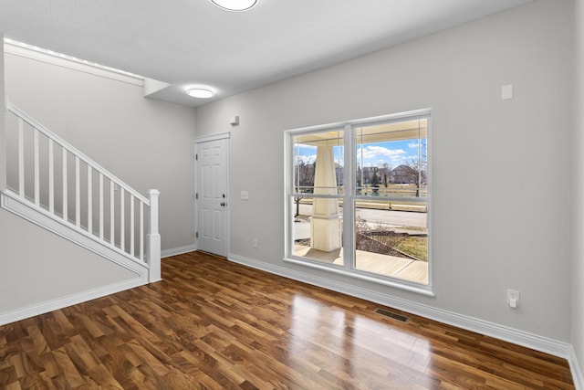 entrance foyer featuring visible vents, baseboards, wood finished floors, and stairs