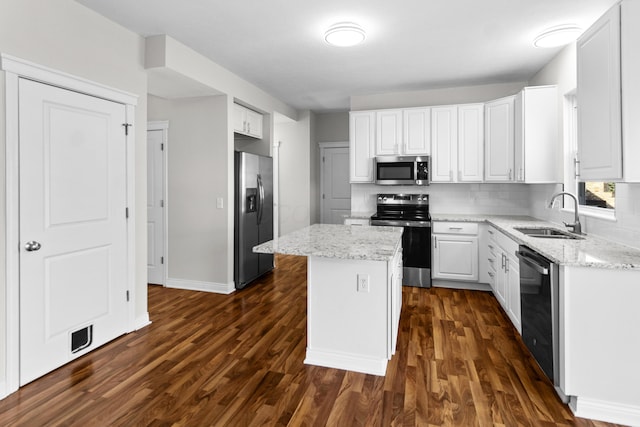 kitchen with a kitchen island, dark wood-type flooring, stainless steel appliances, white cabinetry, and a sink