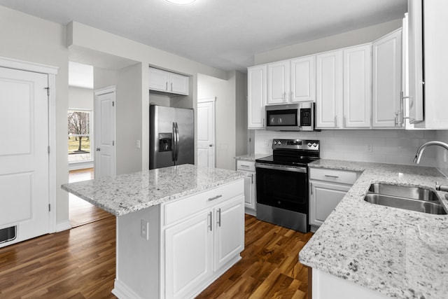 kitchen featuring backsplash, a center island, dark wood-type flooring, appliances with stainless steel finishes, and a sink