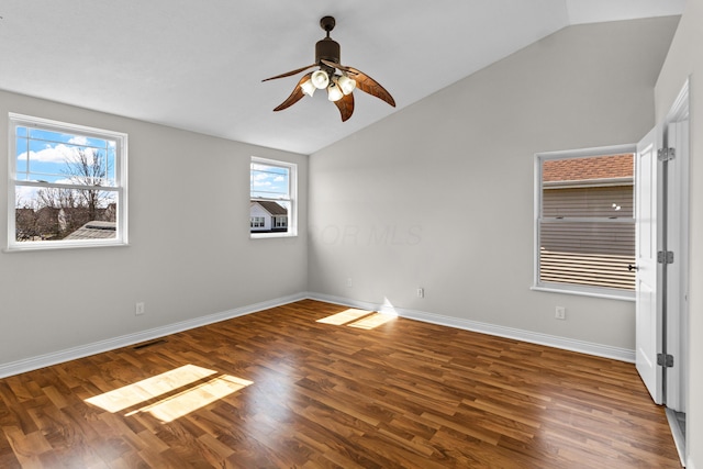 spare room featuring lofted ceiling, wood finished floors, baseboards, and ceiling fan