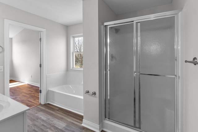 full bathroom with vanity, a shower stall, a garden tub, and wood finished floors