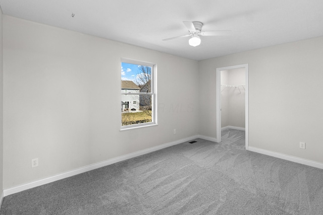 carpeted spare room with baseboards and a ceiling fan