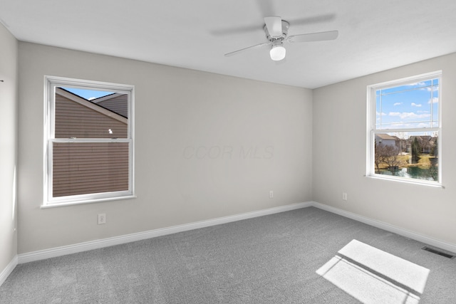 carpeted spare room with baseboards, visible vents, and ceiling fan