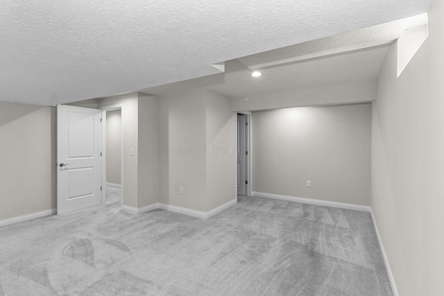 finished below grade area with a textured ceiling, baseboards, and carpet floors