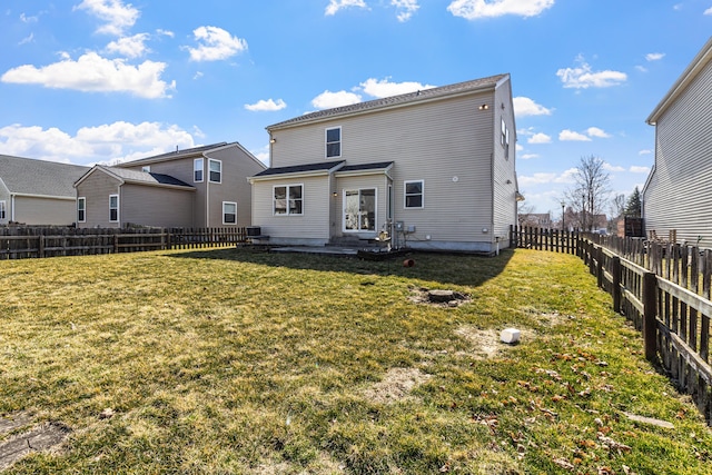 rear view of house featuring a lawn and a fenced backyard