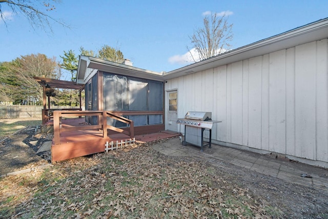 view of side of home with a deck, fence, and a sunroom