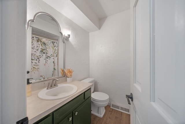 full bathroom with visible vents, toilet, wood finished floors, vanity, and a textured wall