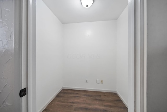 spare room featuring dark wood-type flooring and baseboards