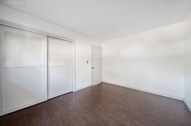 unfurnished bedroom featuring a closet, baseboards, and dark wood-type flooring