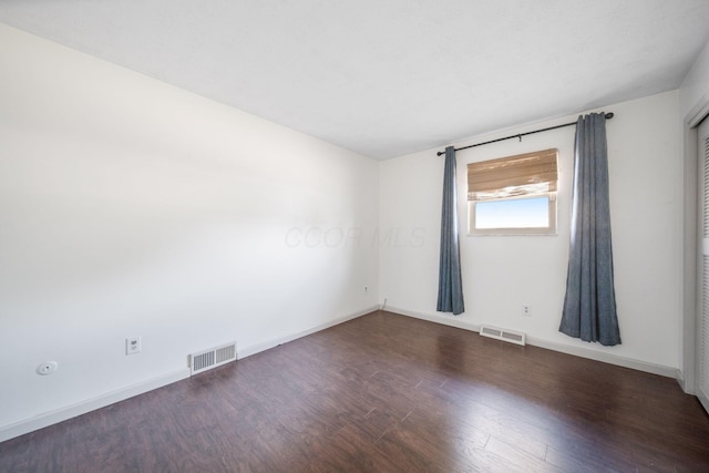 empty room with visible vents, baseboards, and wood finished floors