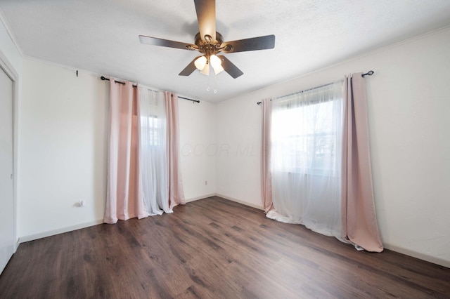 spare room with ceiling fan, dark wood-style floors, baseboards, and a textured ceiling