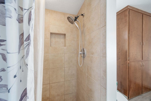 full bathroom featuring tiled shower and a textured ceiling