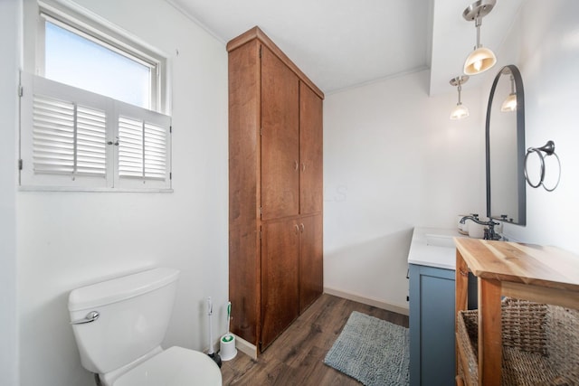 bathroom with vanity, toilet, wood finished floors, and baseboards