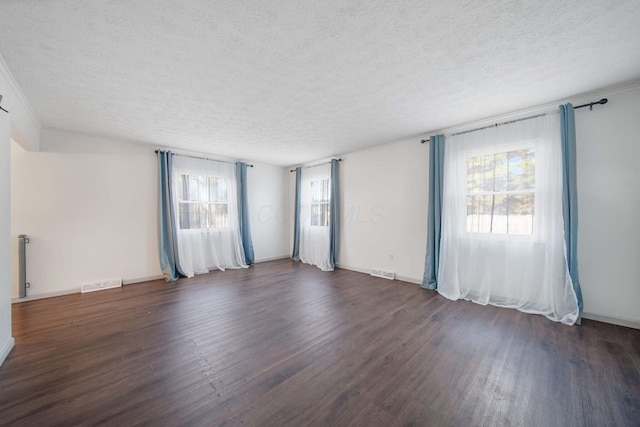 unfurnished room featuring wood finished floors, visible vents, and a textured ceiling