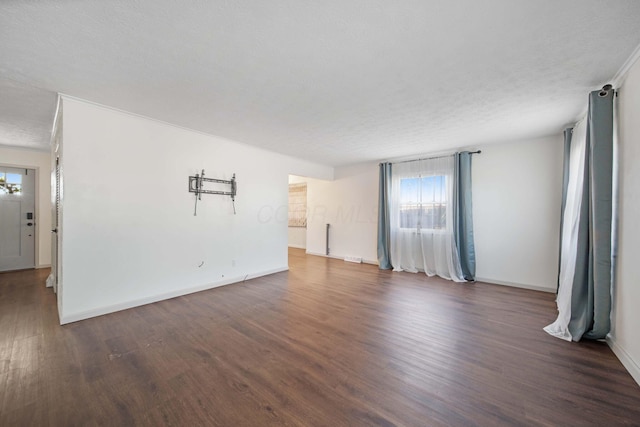 unfurnished living room featuring baseboards, a textured ceiling, and wood finished floors