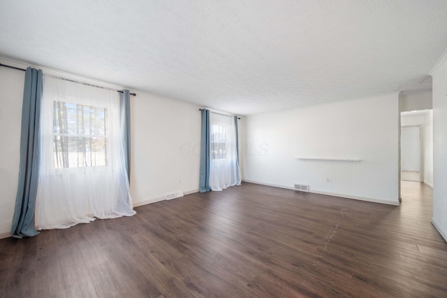 empty room with visible vents, a textured ceiling, and wood finished floors