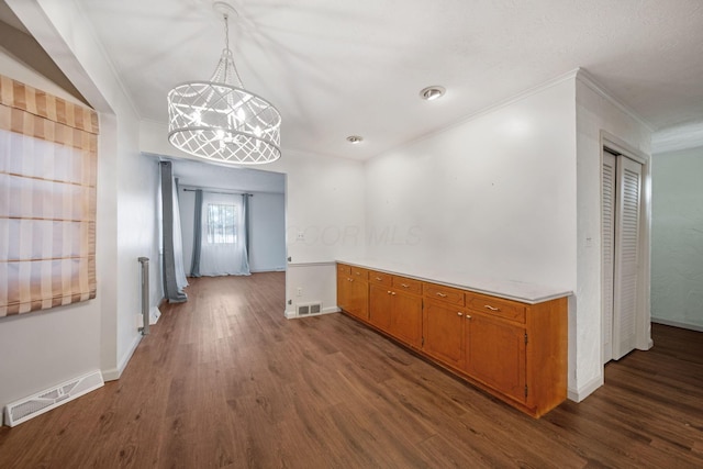 hallway featuring a chandelier, visible vents, dark wood-style floors, and ornamental molding