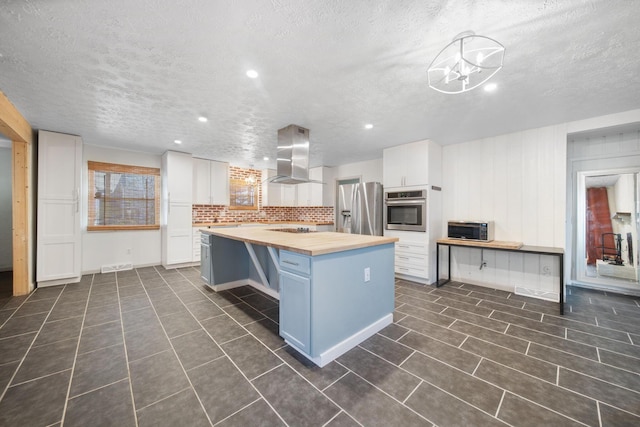 kitchen with a kitchen island, extractor fan, appliances with stainless steel finishes, wood counters, and white cabinetry