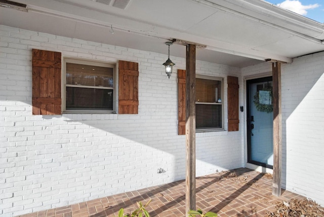 entrance to property featuring visible vents and brick siding