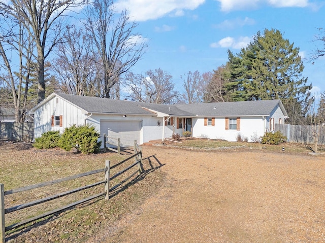 single story home featuring an attached garage, fence, board and batten siding, and driveway