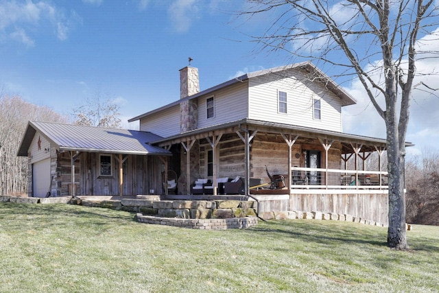 rear view of house featuring a lawn, stone siding, a porch, a garage, and a chimney